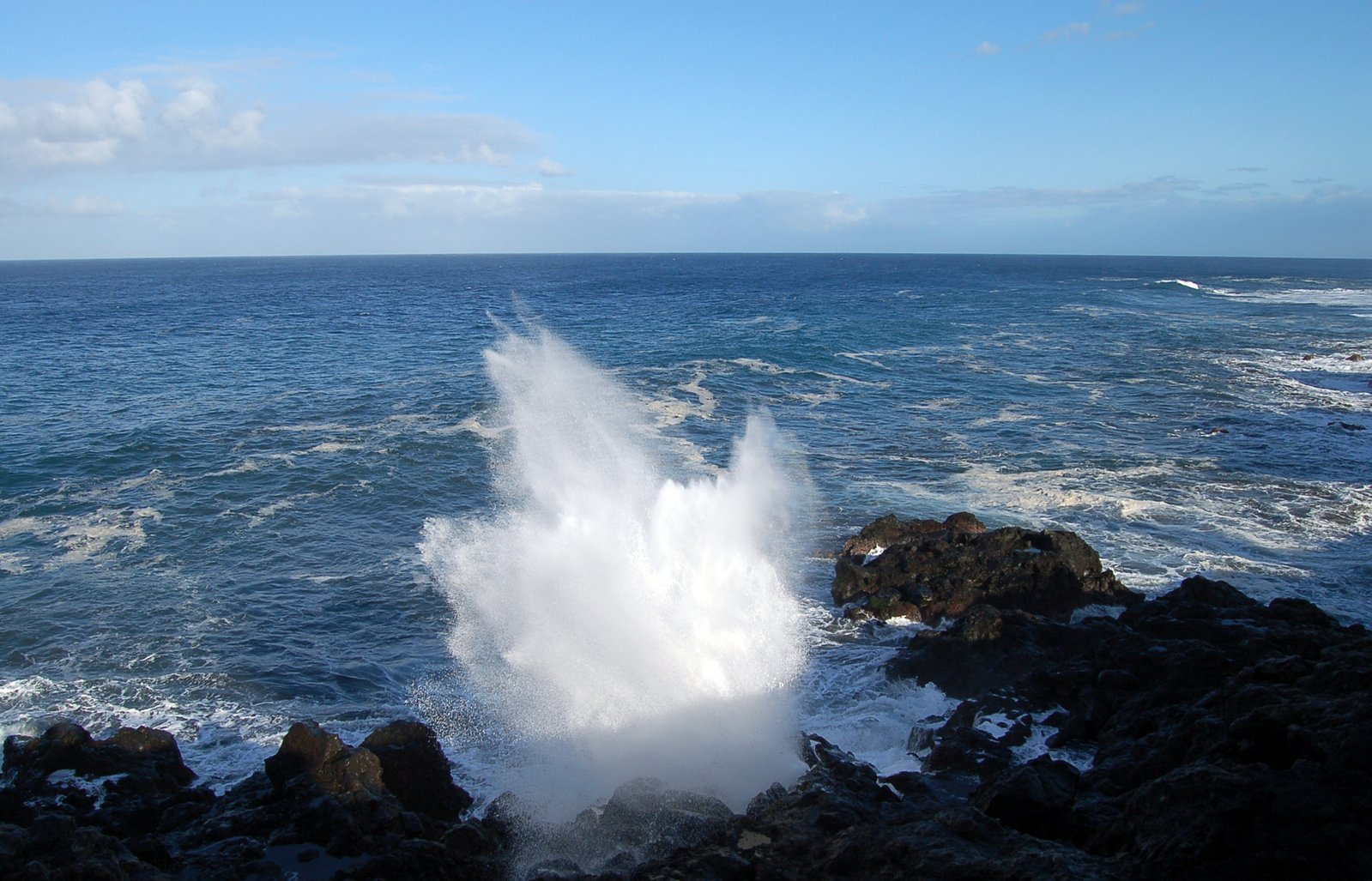 a large body of water spewing out of a rocky shore