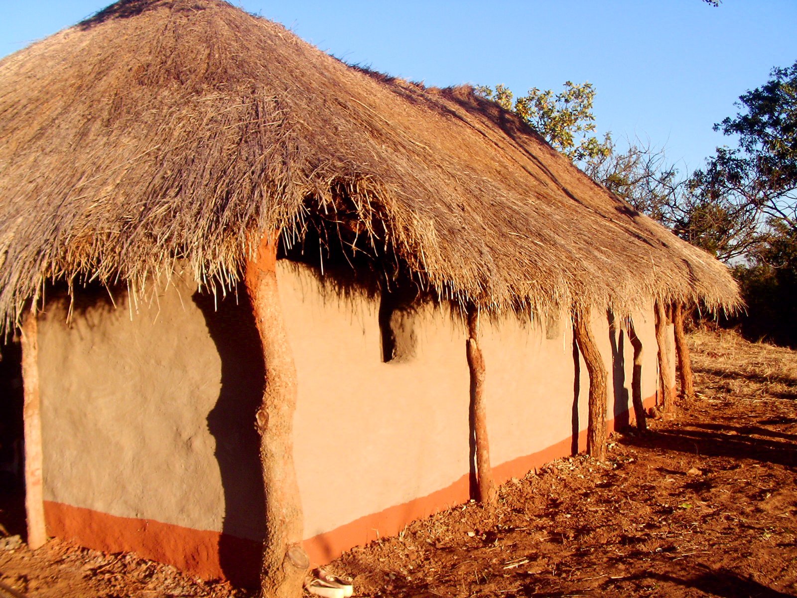 a brown adobe building with a large straw roof