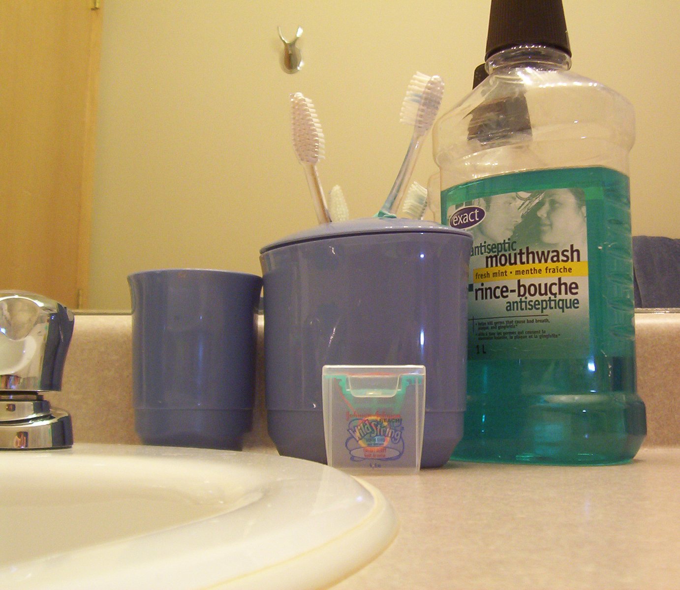 there are many toothpastes and a cup in the bathroom