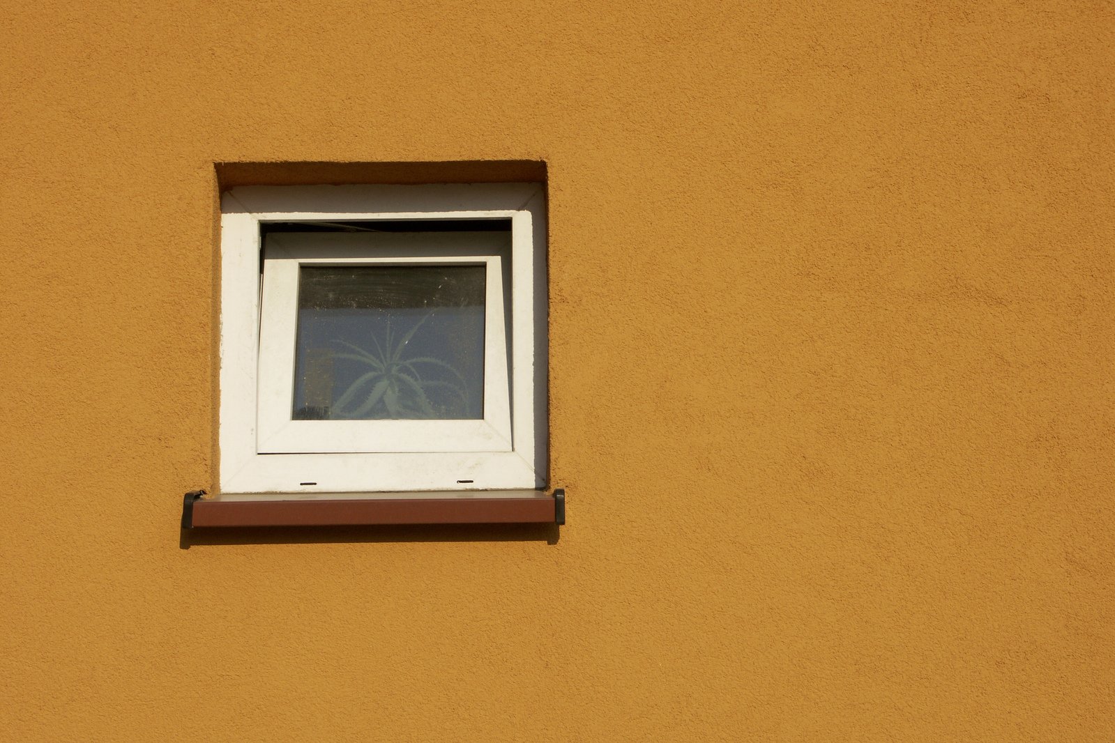 a yellow wall with a white window in it