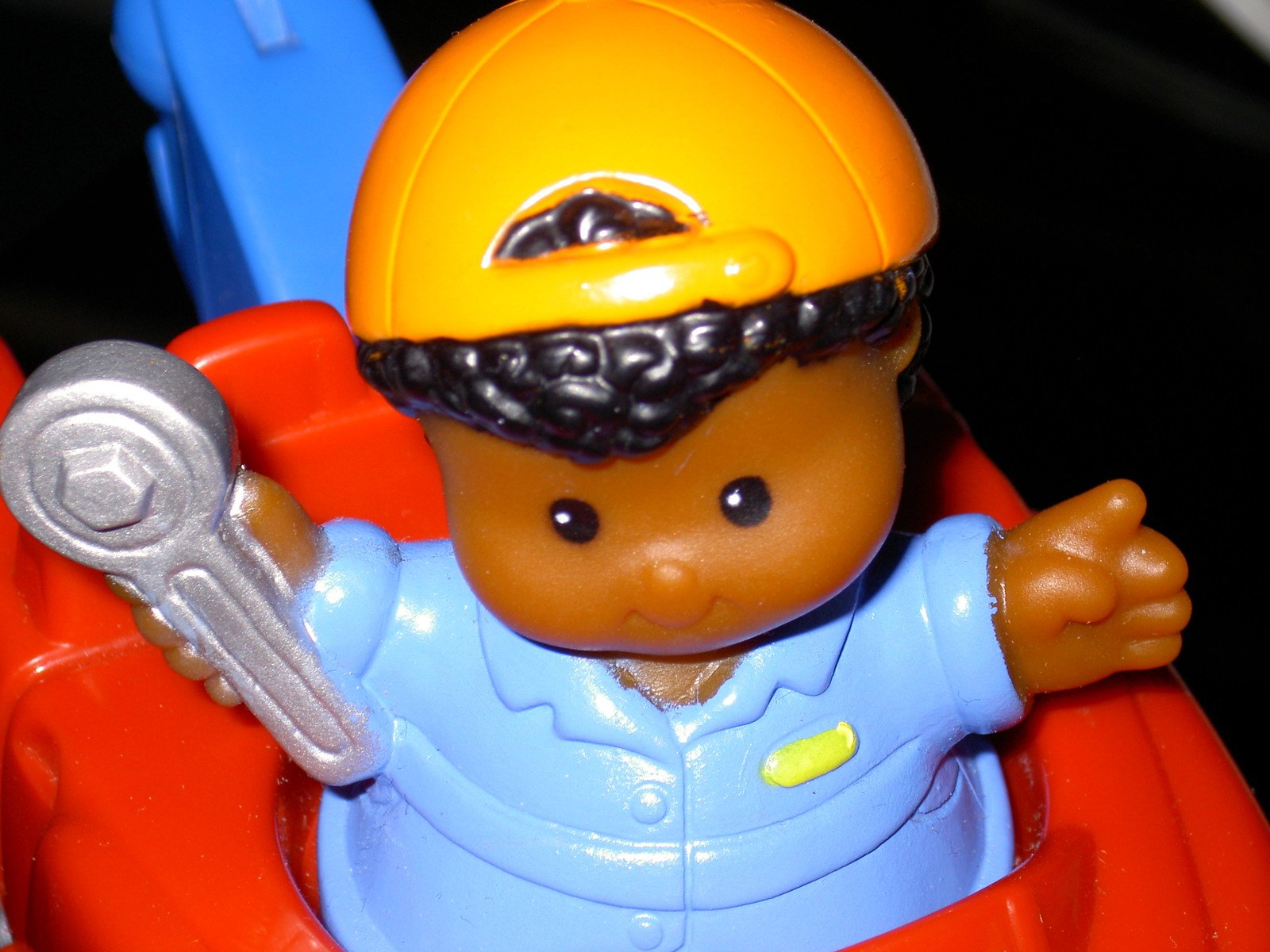 an orange toy doll in safety gear holding a wrench