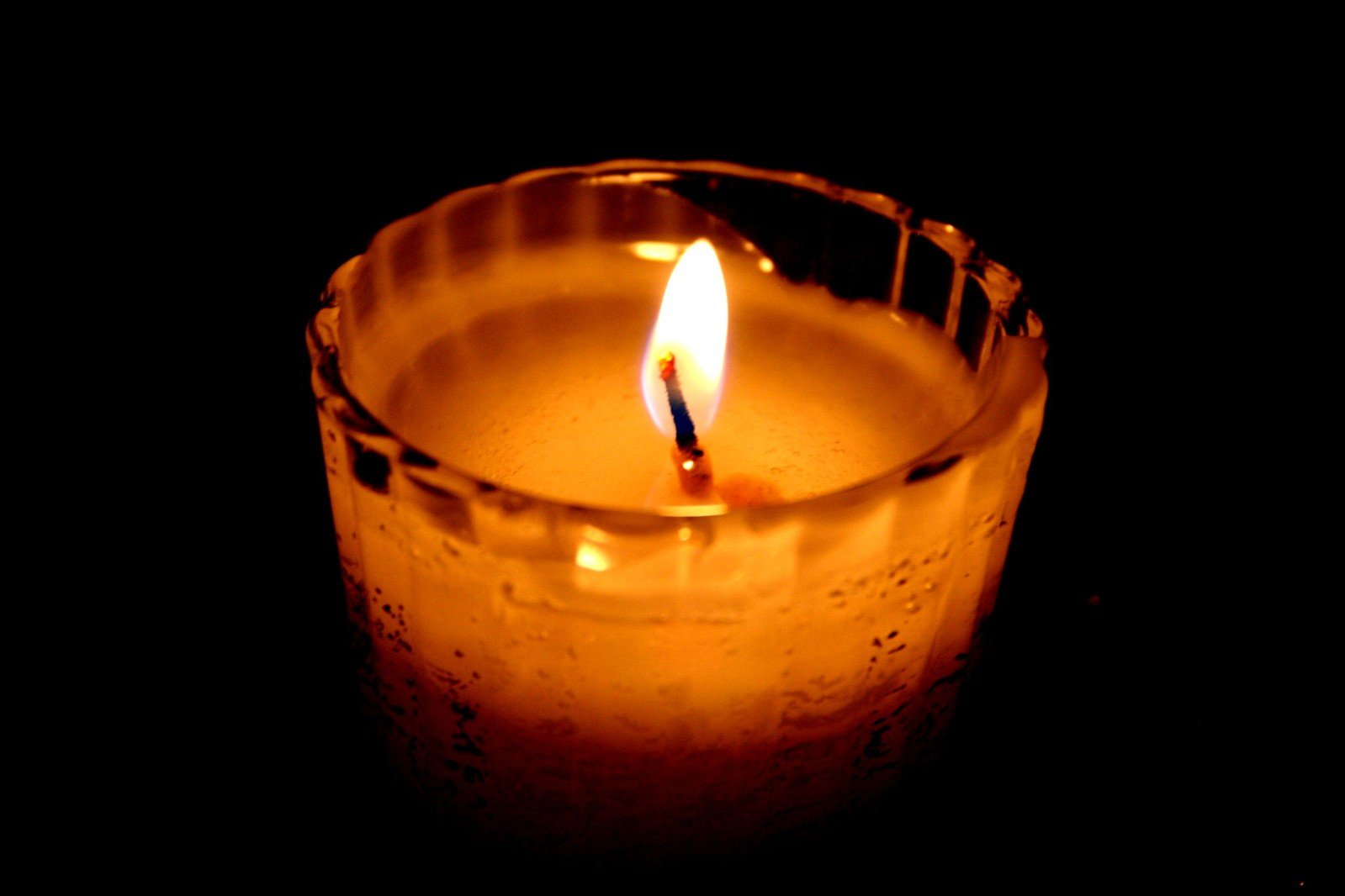 a lit candle with water inside it on a black background