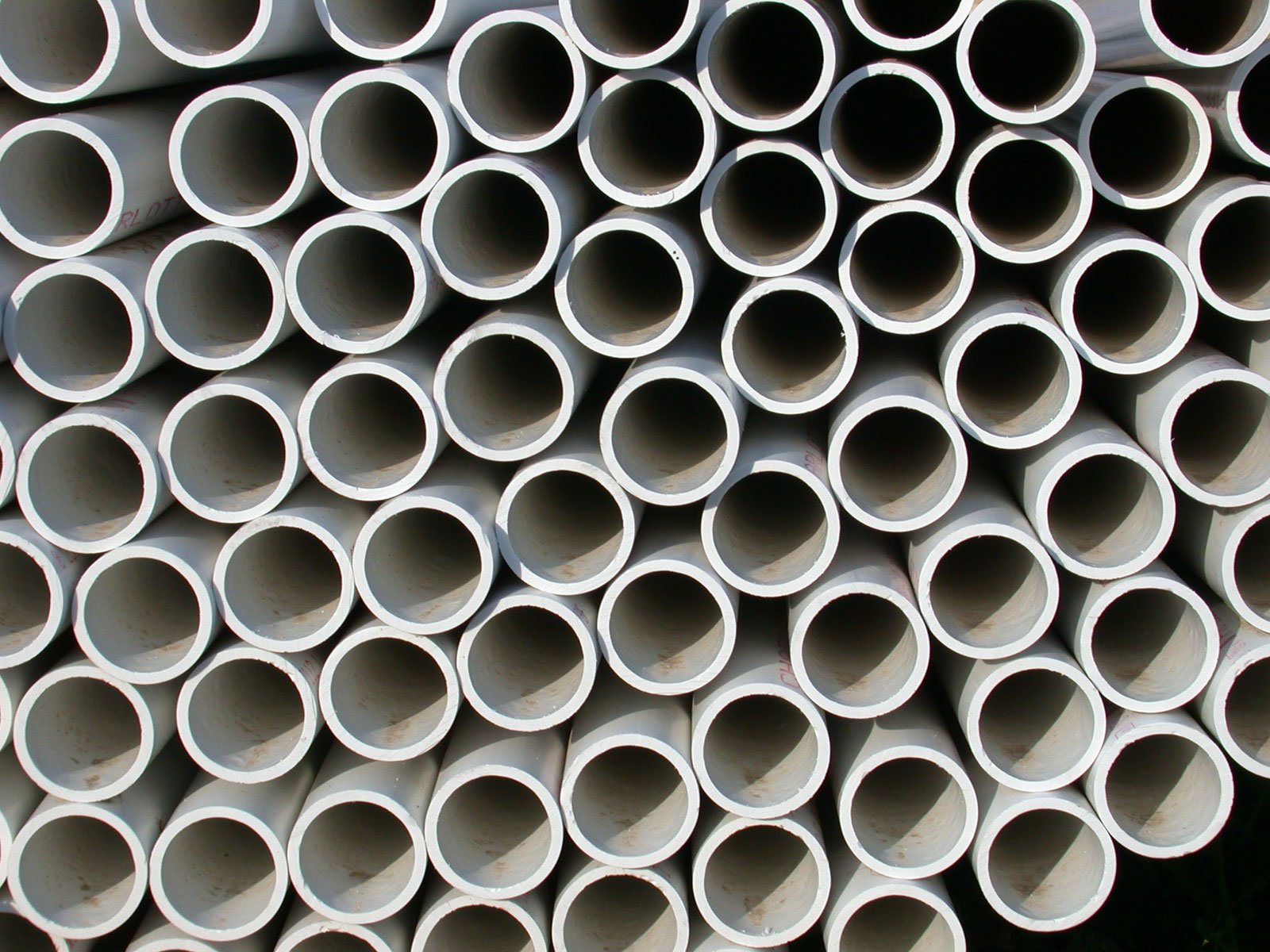 white piping are stacked up to be used for drainage