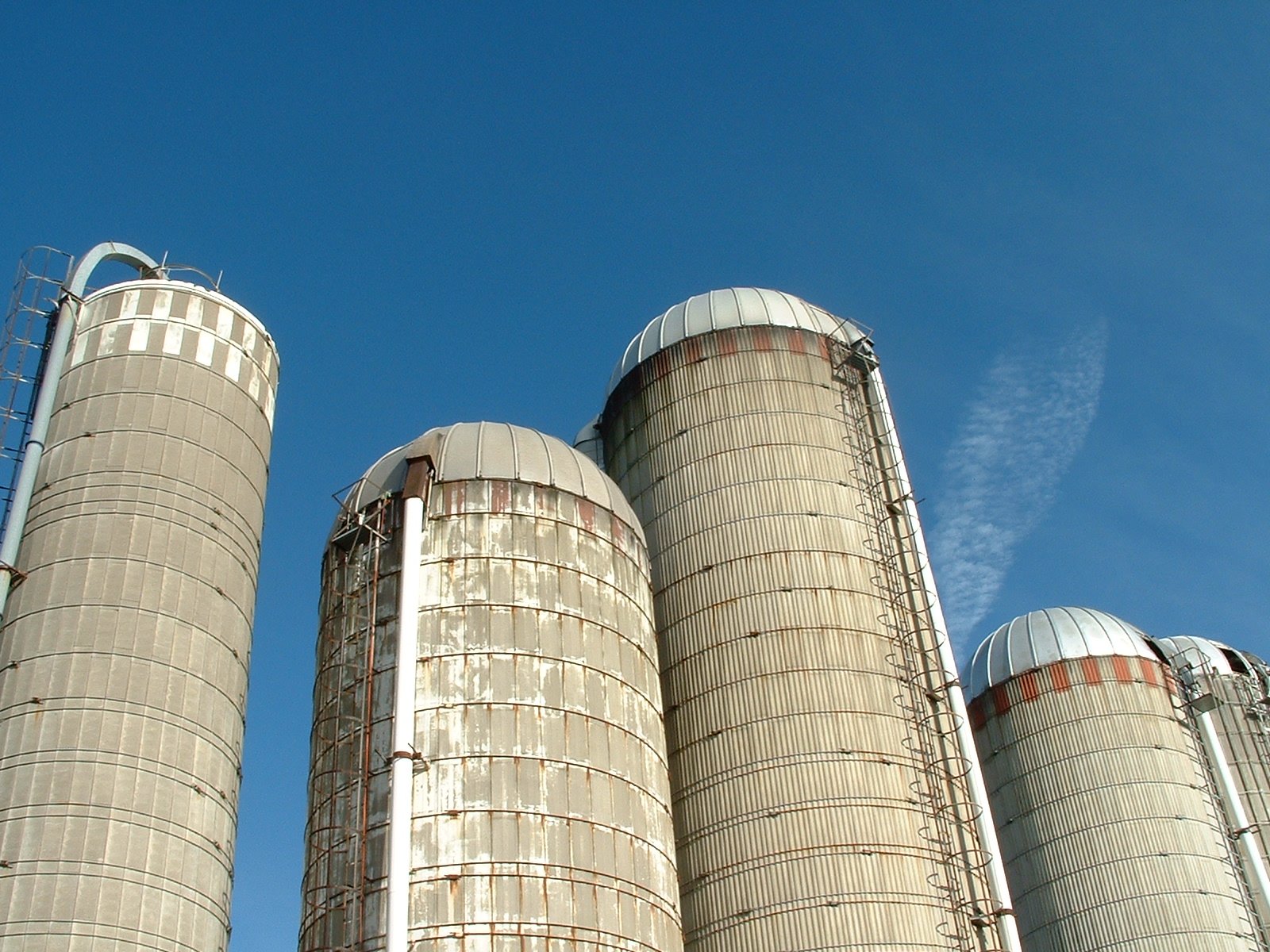 large metal silos against a blue sky and white clouds