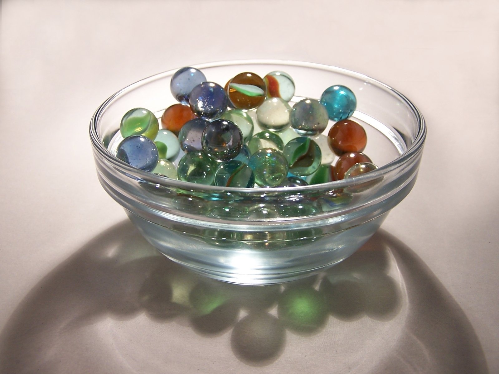 many marbles in a bowl on a shiny surface