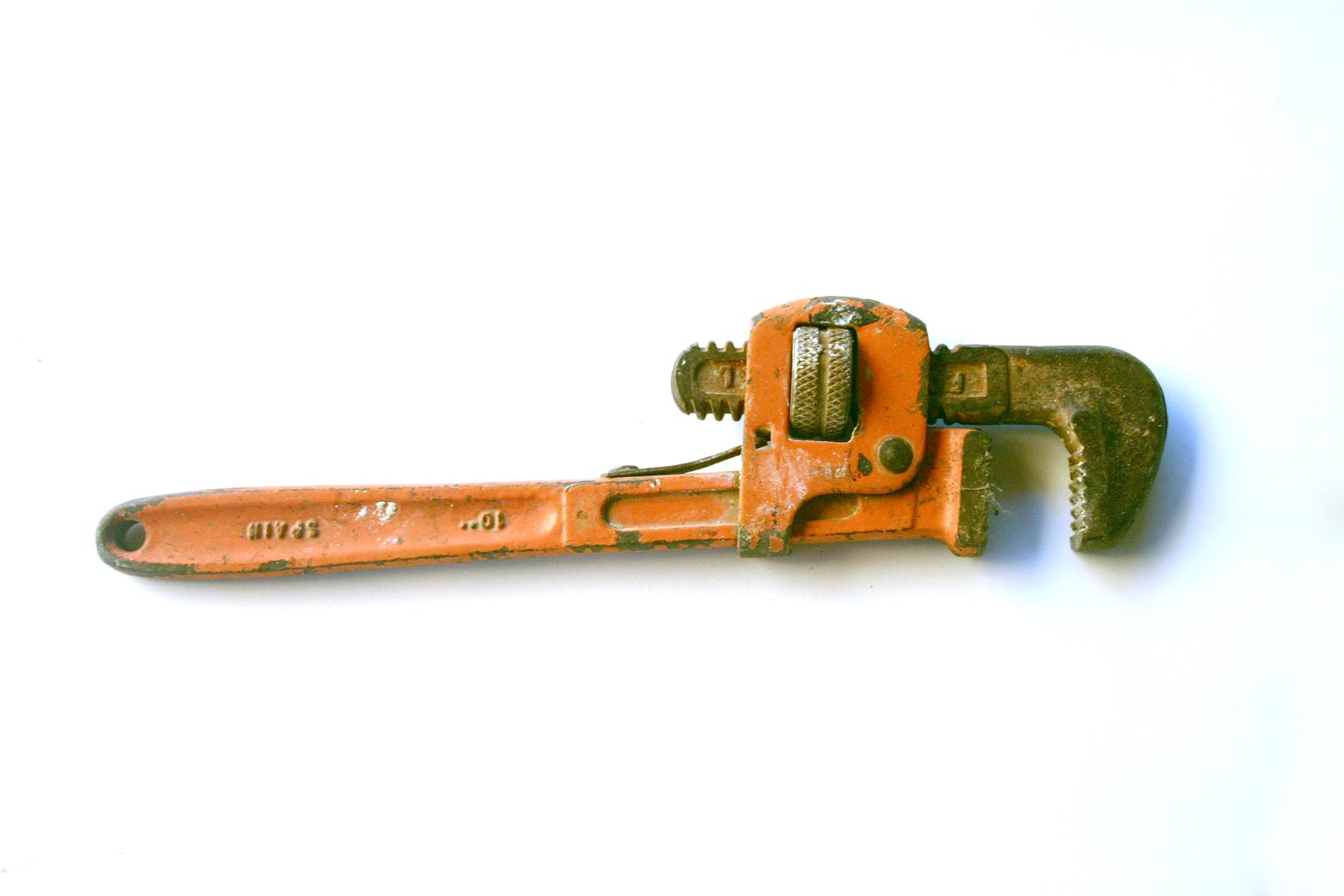 an orange hand tool resting on a white wall