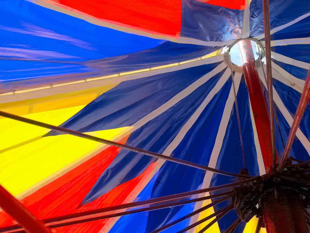 a colorful striped umbrella that is open in the sunlight