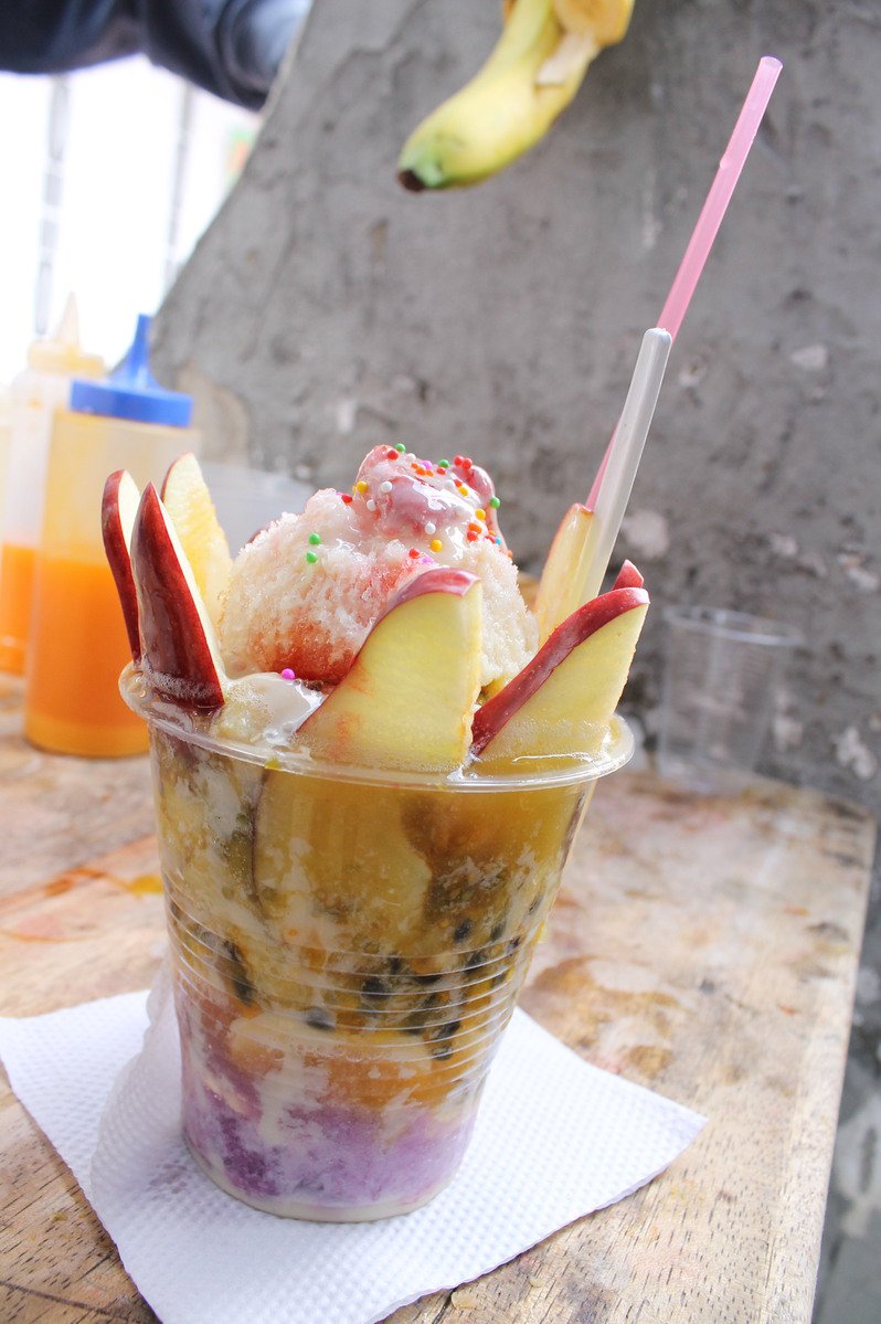 a colorful dessert in a plastic cup with a straw and plastic straw