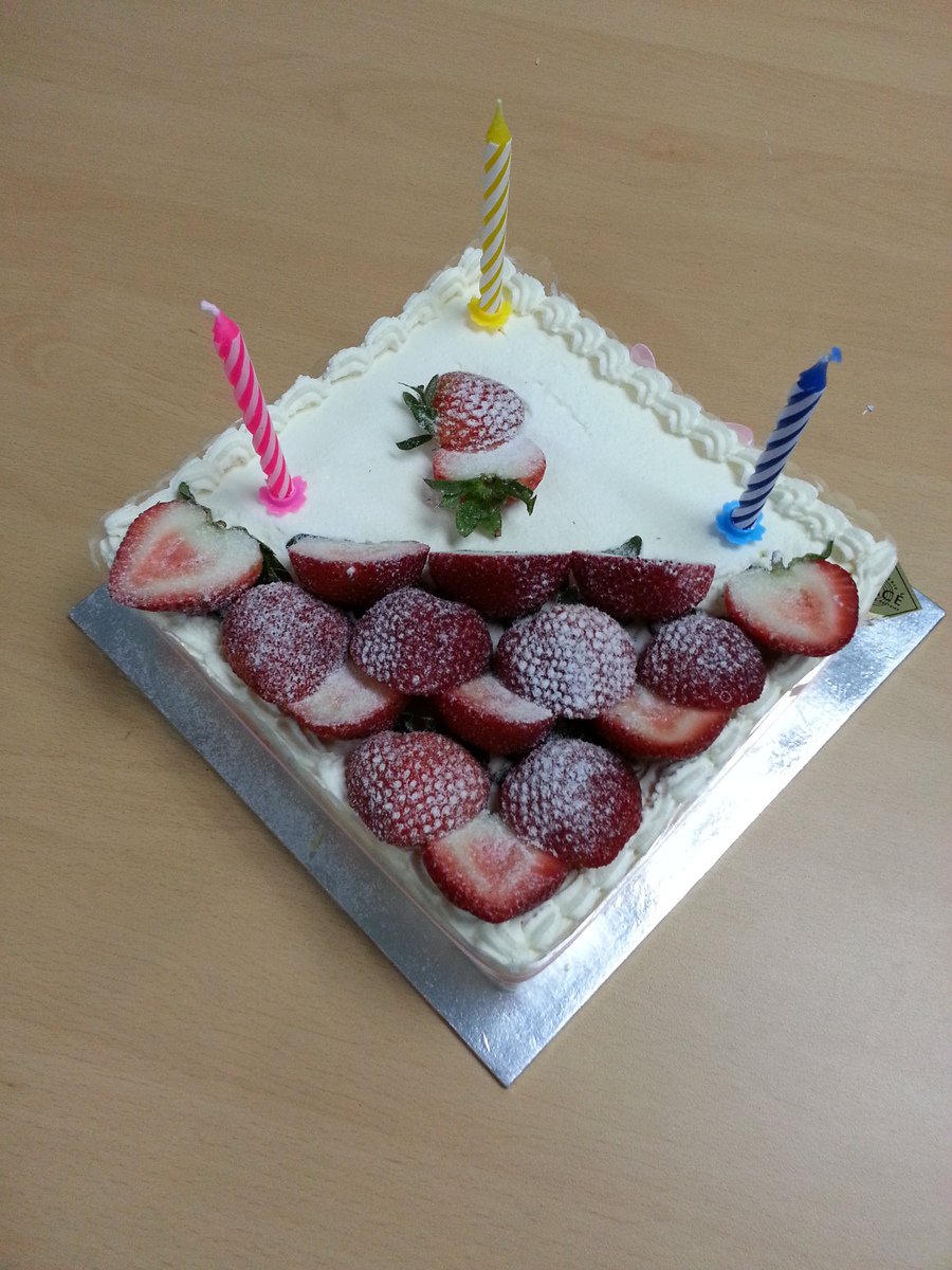 this white strawberry cake is topped with white icing and has two candles