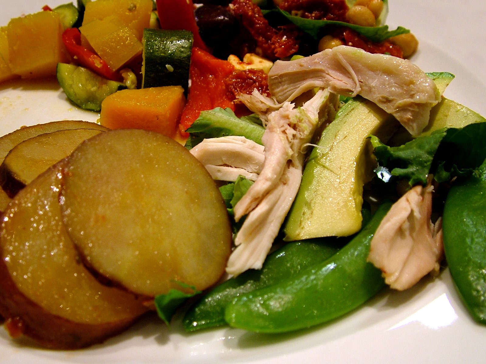 a plate filled with meat, vegetables and cut up cucumbers