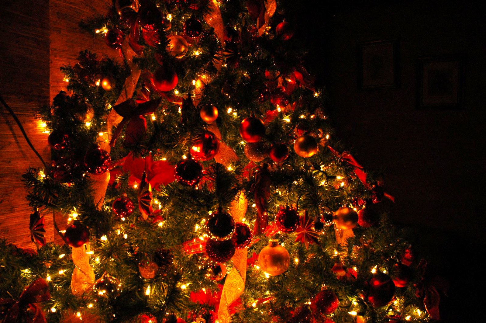 lit christmas tree decorated with ornaments in dark room