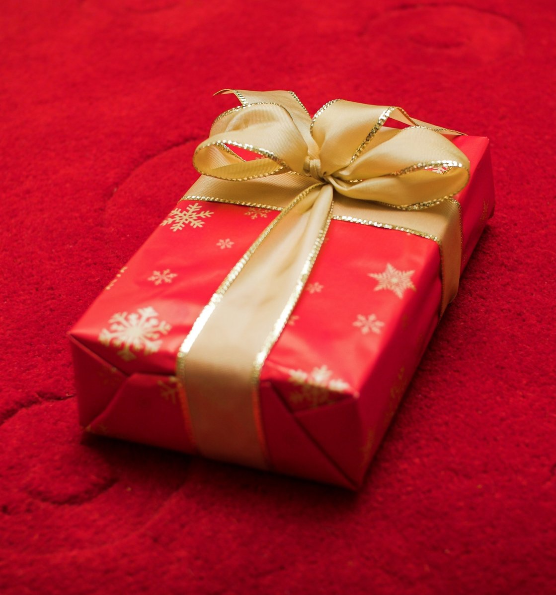 a red wrapped present on top of a red tablecloth