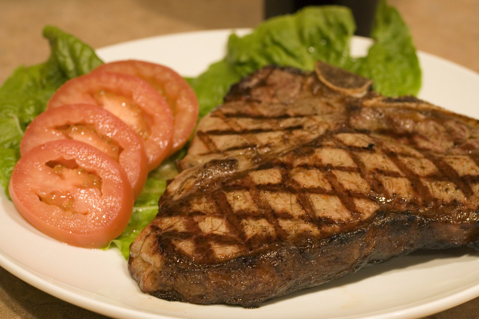 plate of steak and lettuce with tomato on side