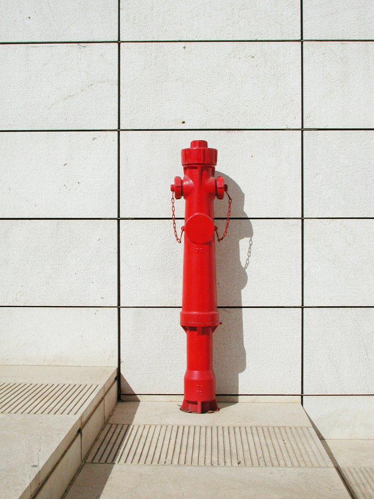 a red fire hydrant against a wall and stairs