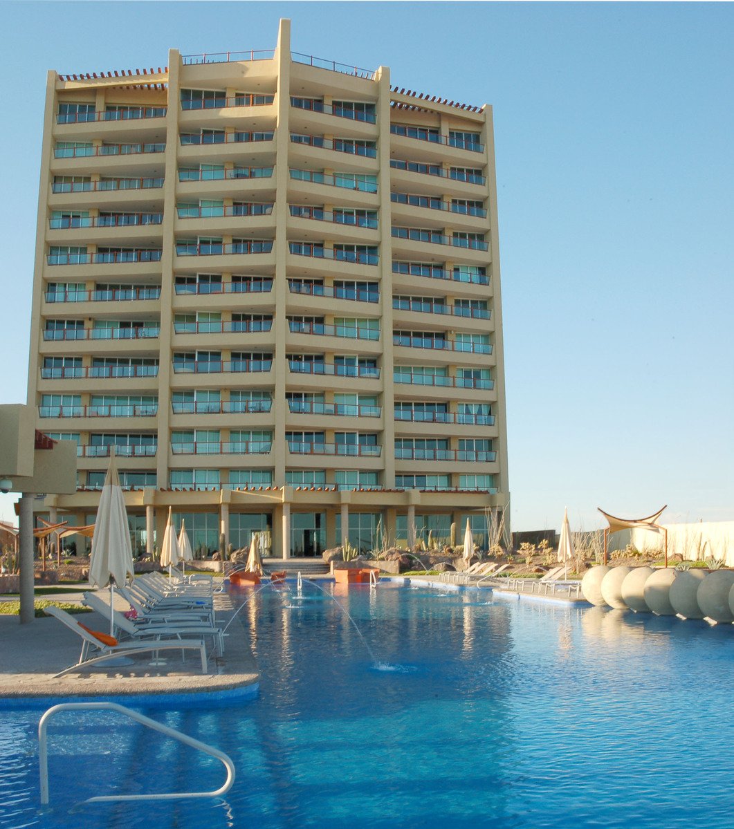 an outdoor swimming pool with chaise lounge chairs and swimming pool in front of large multi - story building