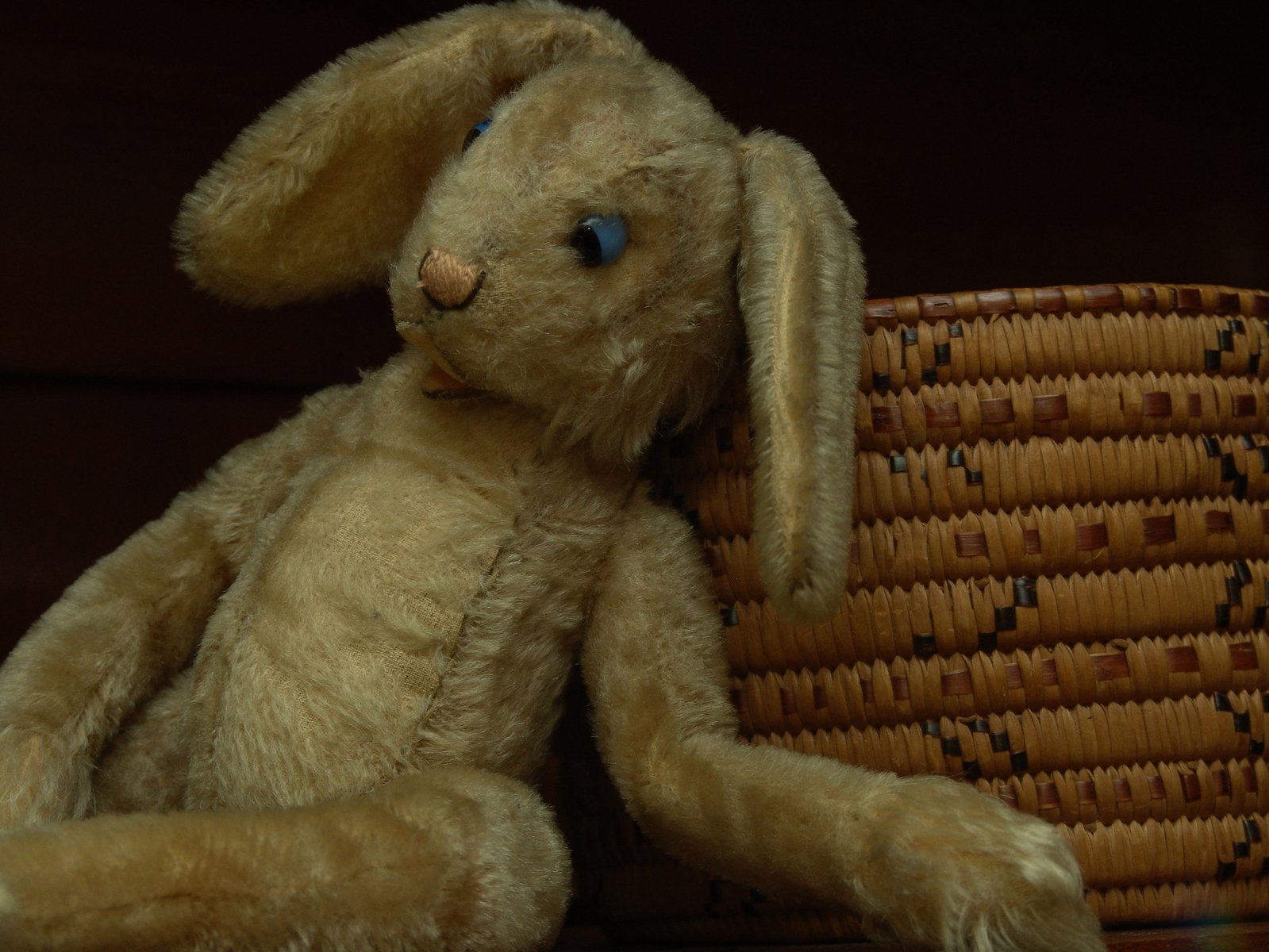 a small stuffed rabbit sits next to an empty basket