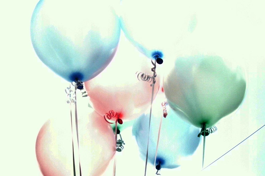 many balloons in pastel blue and pink arranged on poles