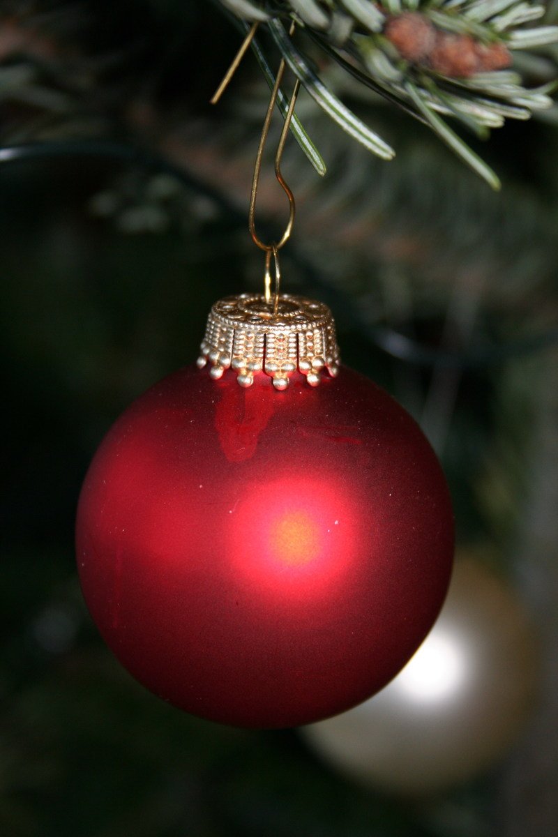 a red ball ornament hanging on a christmas tree