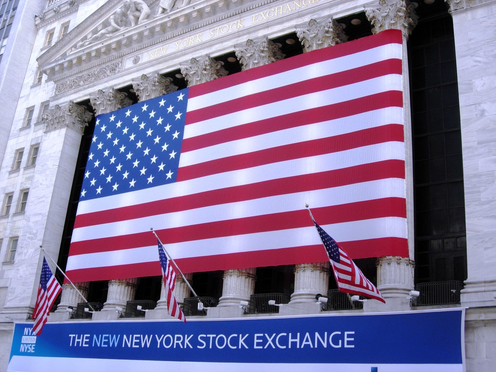 several american flags in front of an building on new york stock exchange