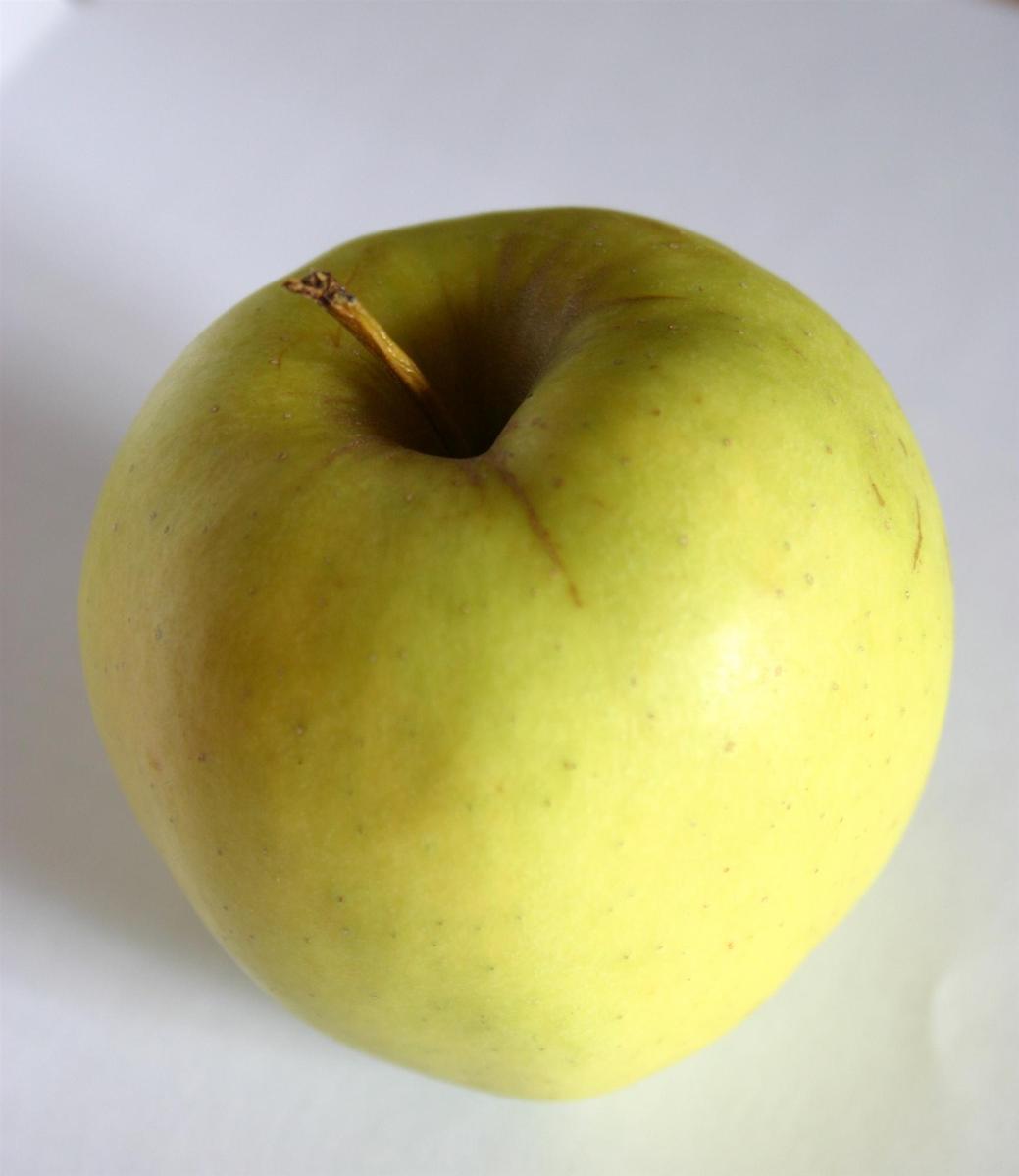 the top of a green apple on a white surface