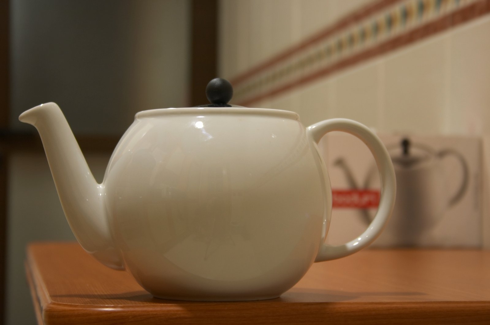 a white tea pot sitting on top of a wooden table