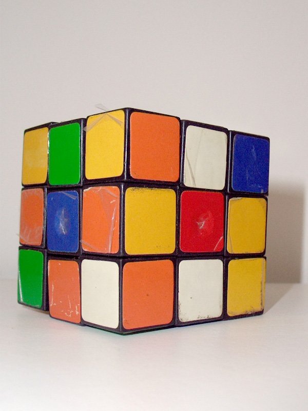 a multicolored cube is standing upright on a white surface