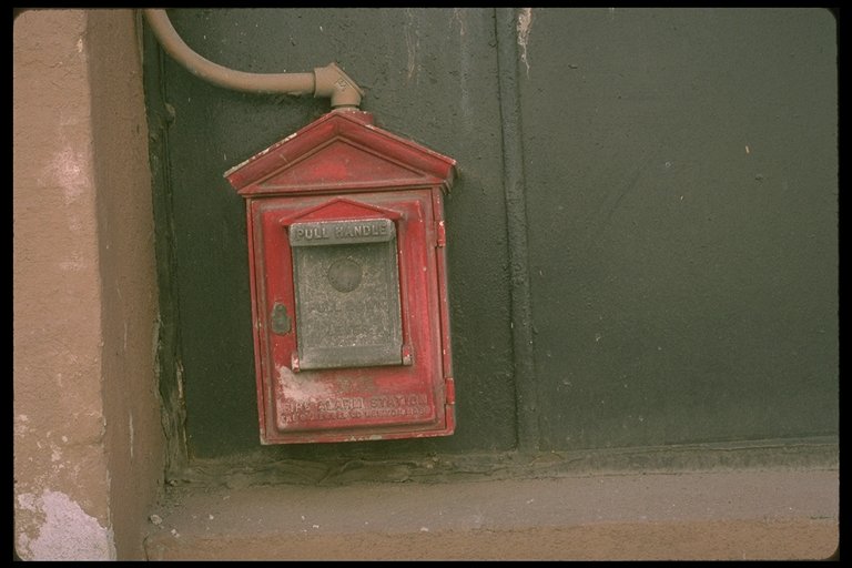 a red mailbox mounted on a wall in front of a green door