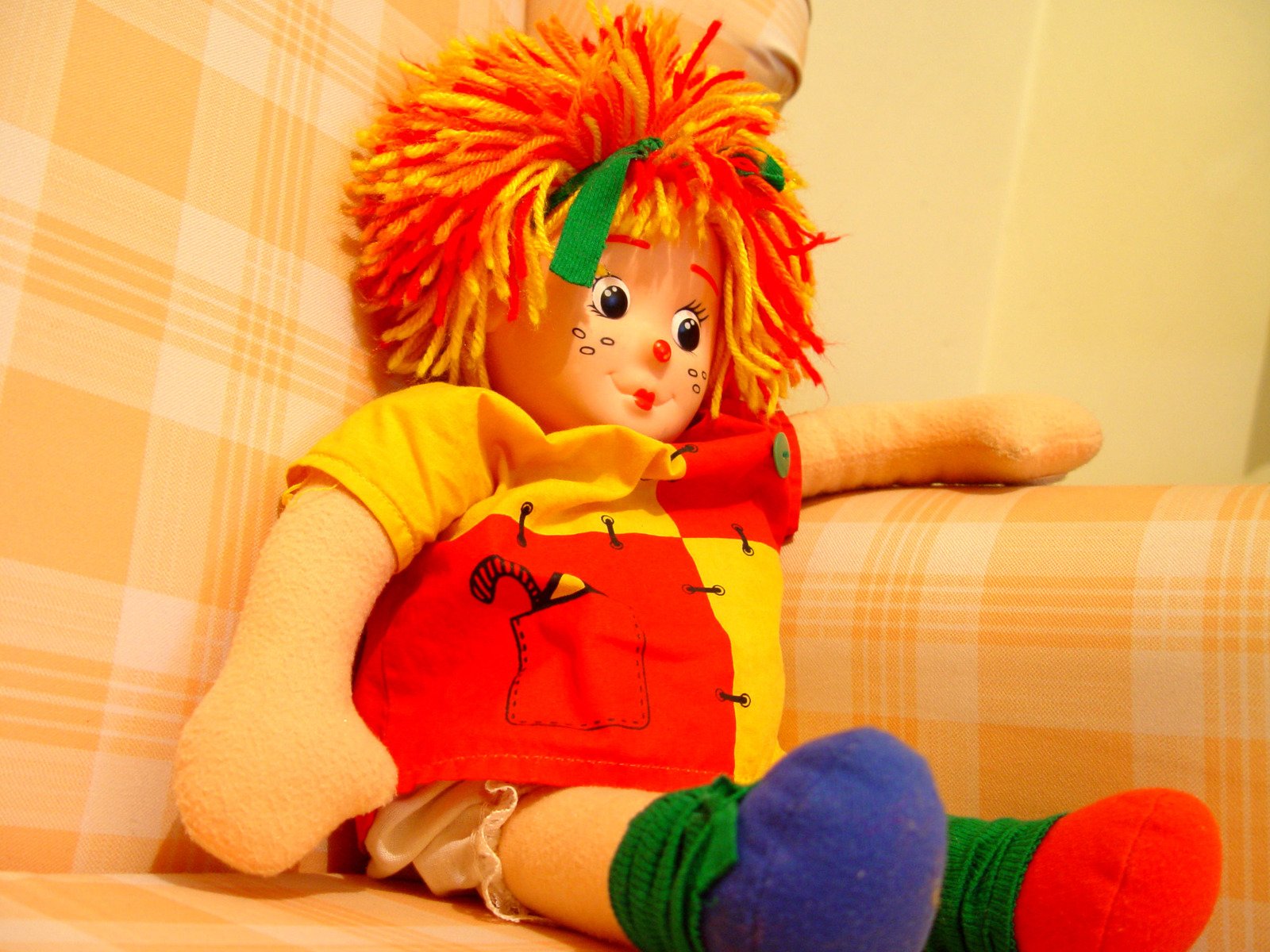 a little boy doll with colorful hair sitting on a chair