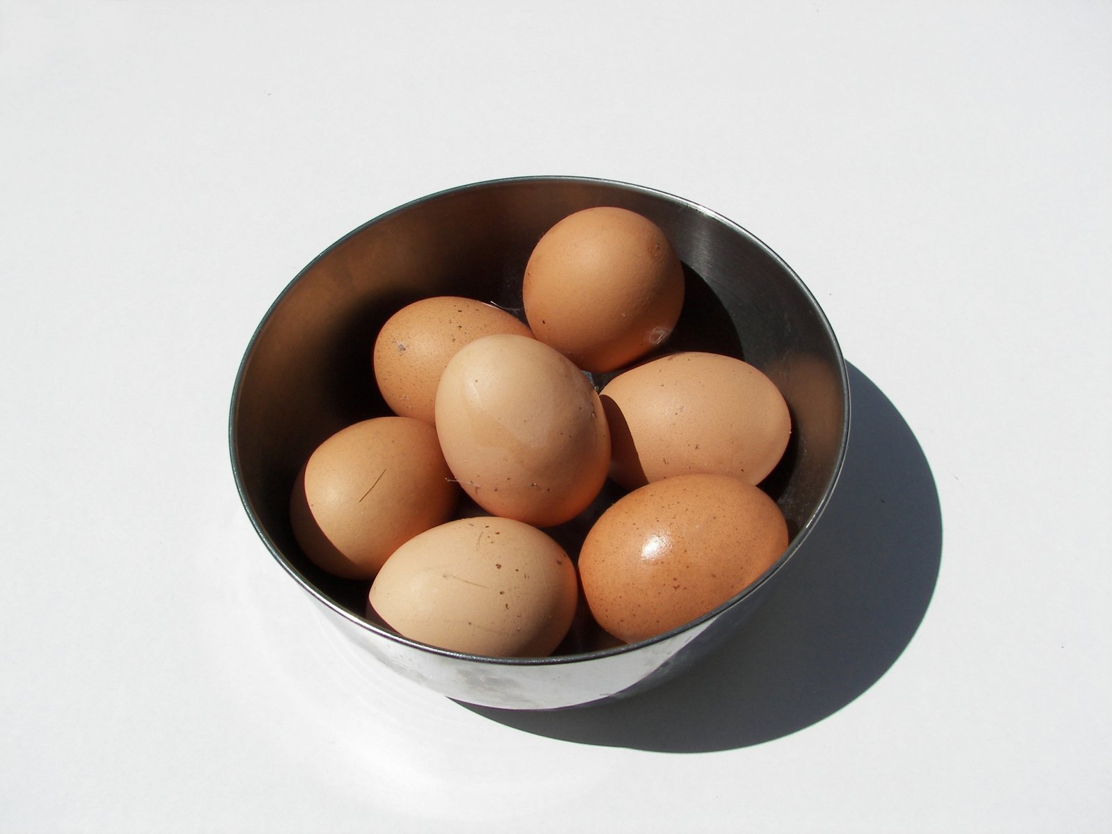 a silver bowl of brown eggs on top of a table