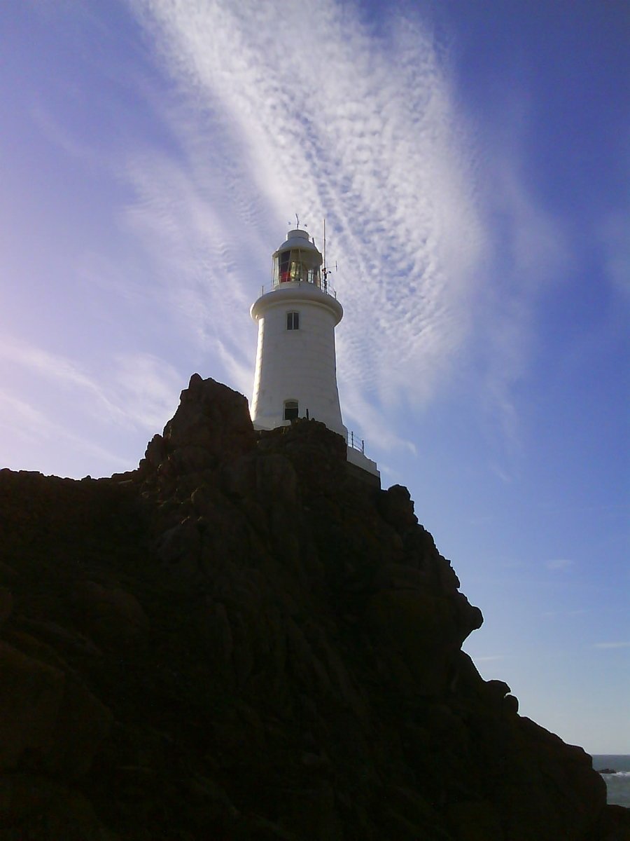 a light house sitting on the side of a large hill