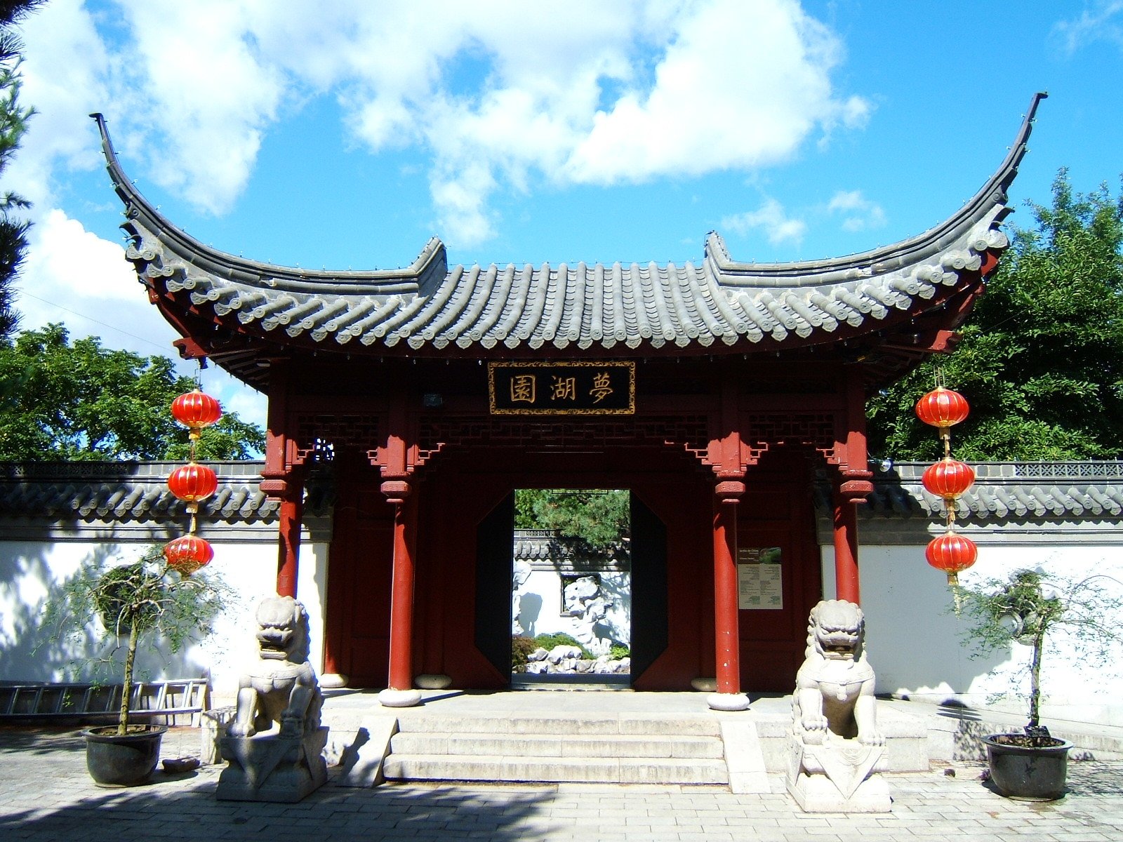 an asian gate with lanterns hanging outside of it