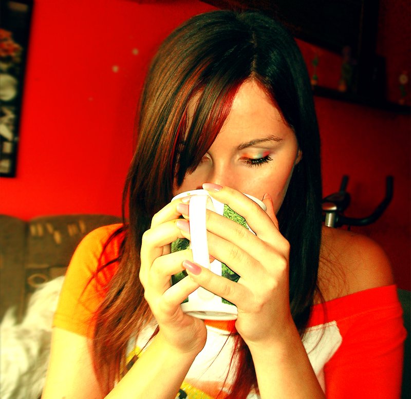 a woman holding a cup to her mouth and looking away from the camera
