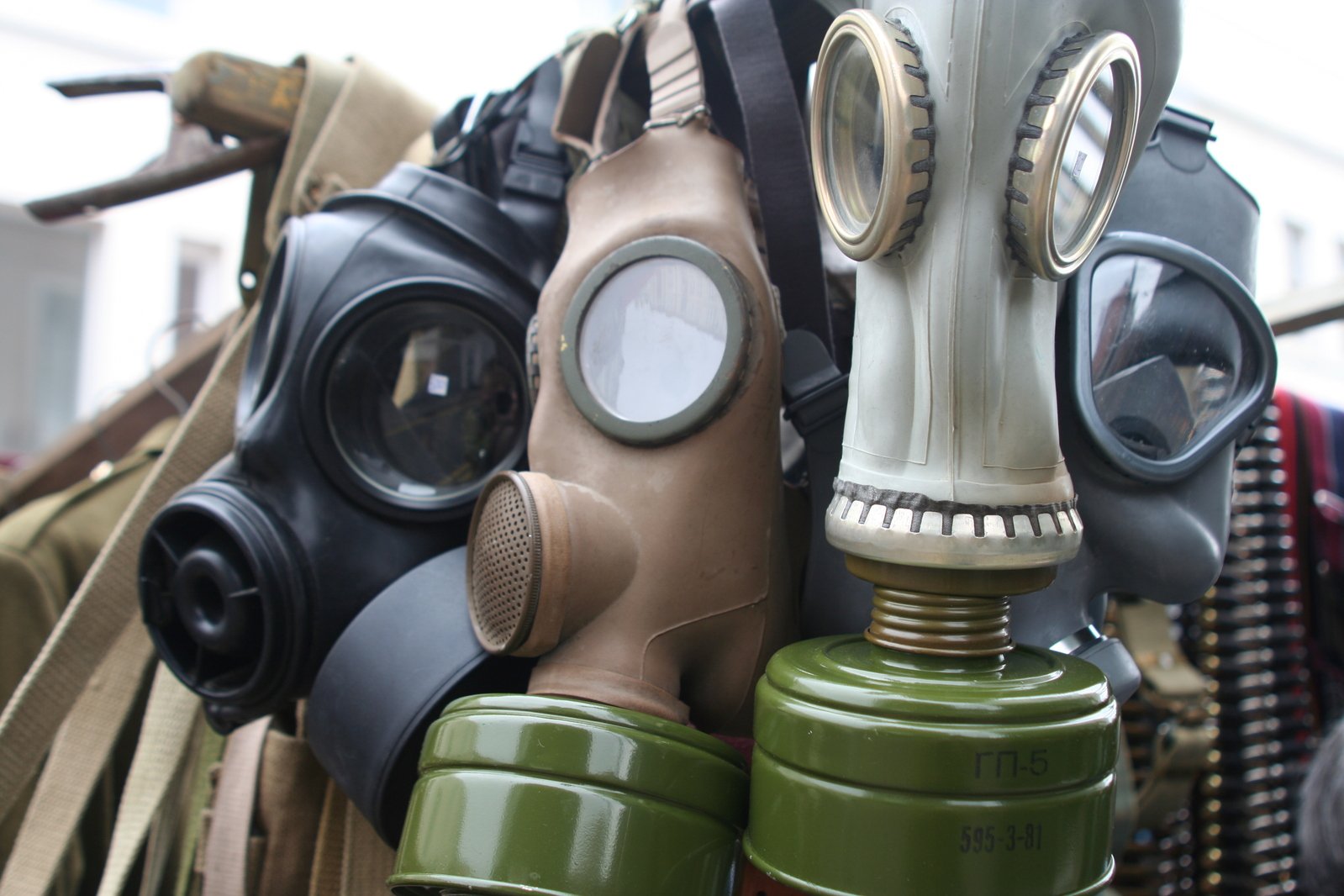 a group of gas masks hanging on clothes