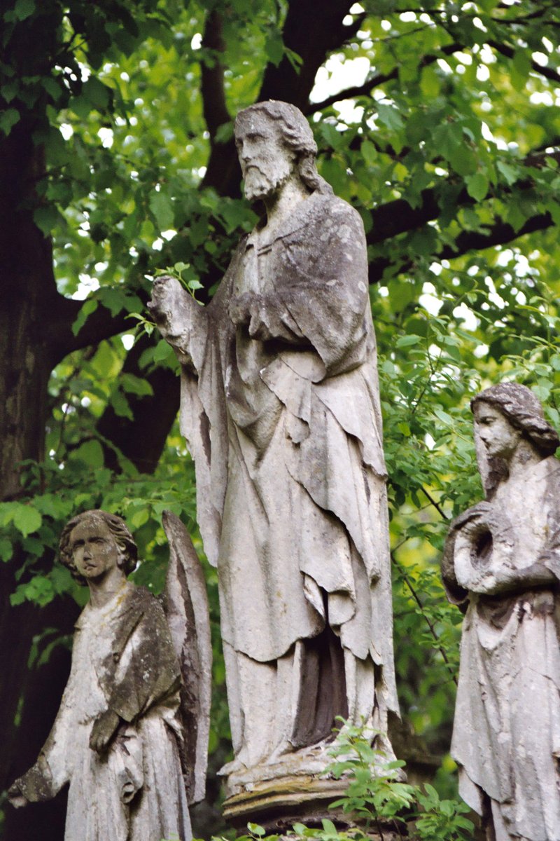 three statues of people holding hands behind a tree