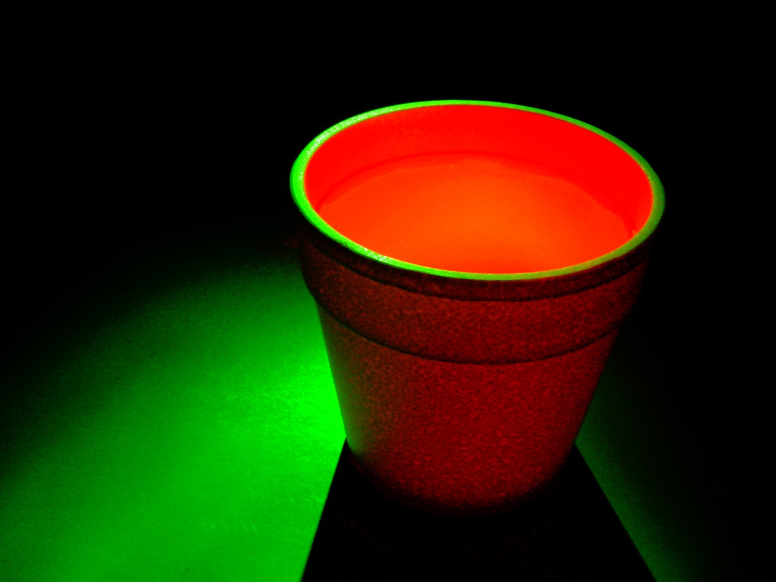 a green lit cup with a black background