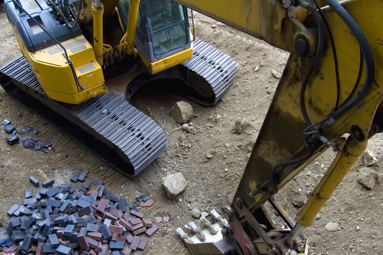 two construction vehicles parked on dirt with lots of rubble