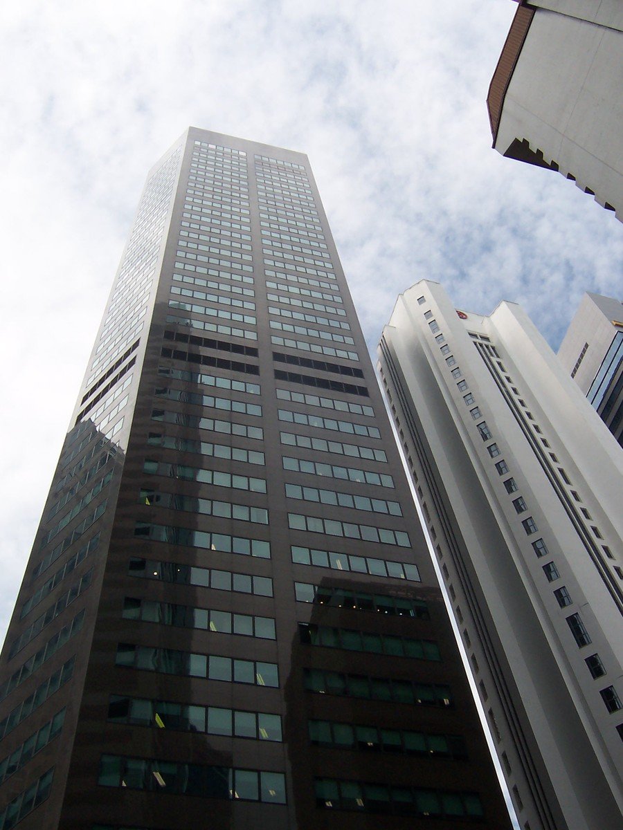 a few very tall buildings in front of a cloudy sky