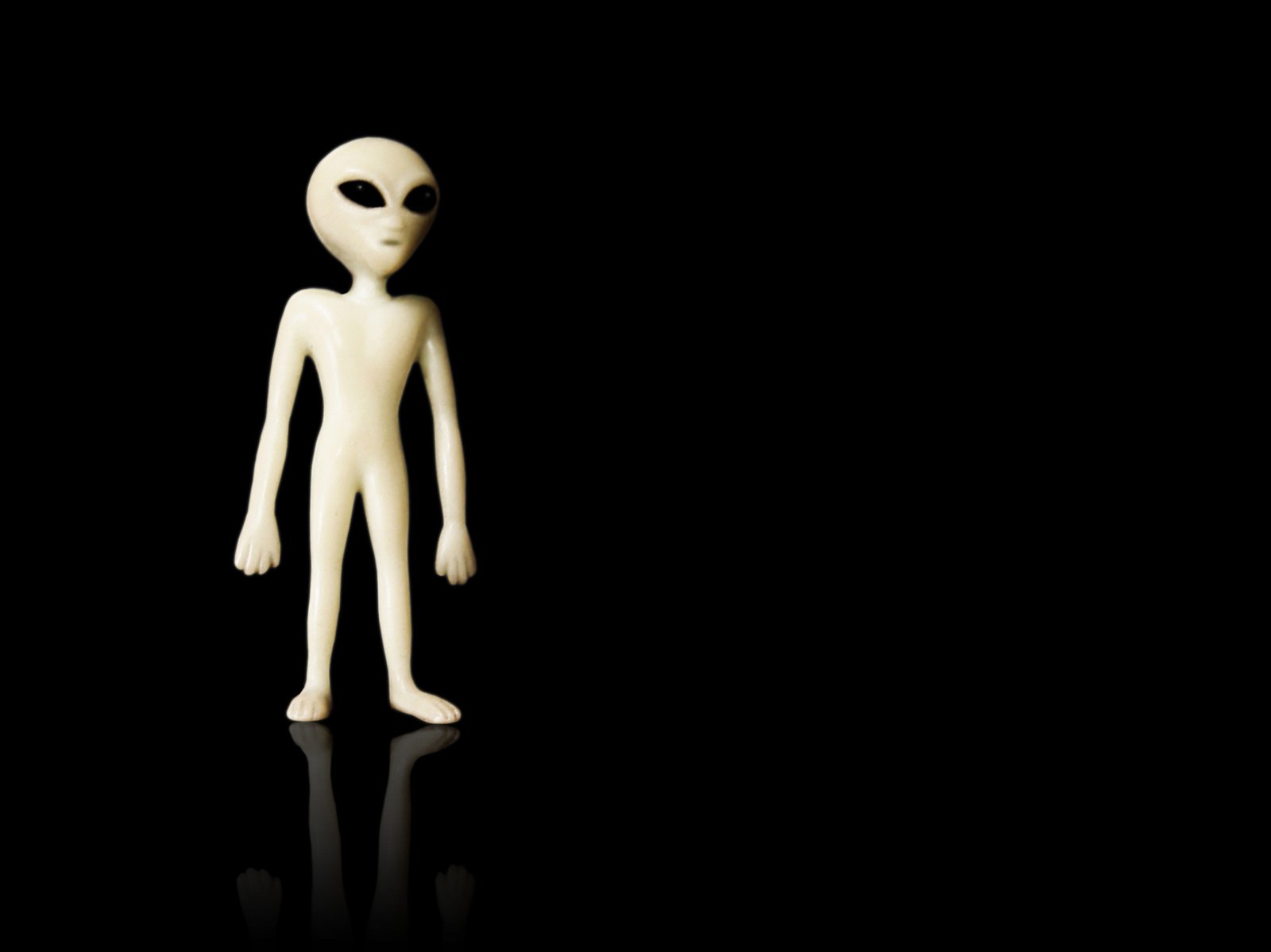 a white alien doll standing in the dark