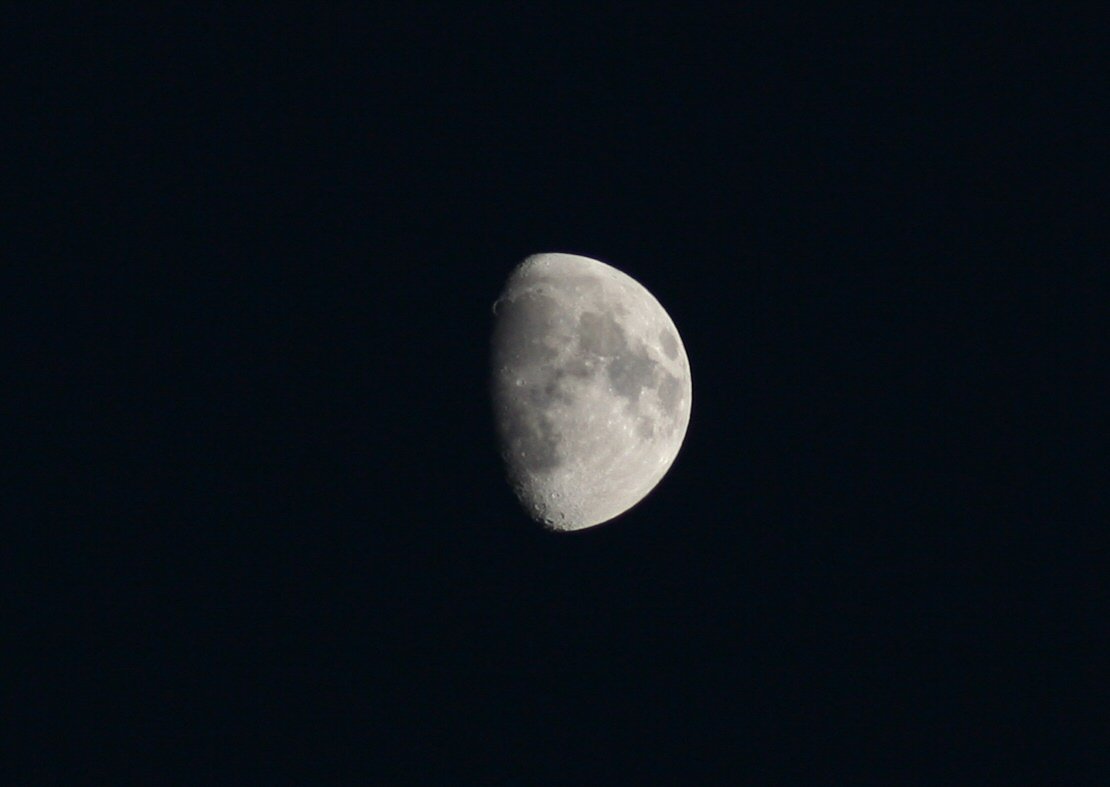 a half moon is lit up in the night sky