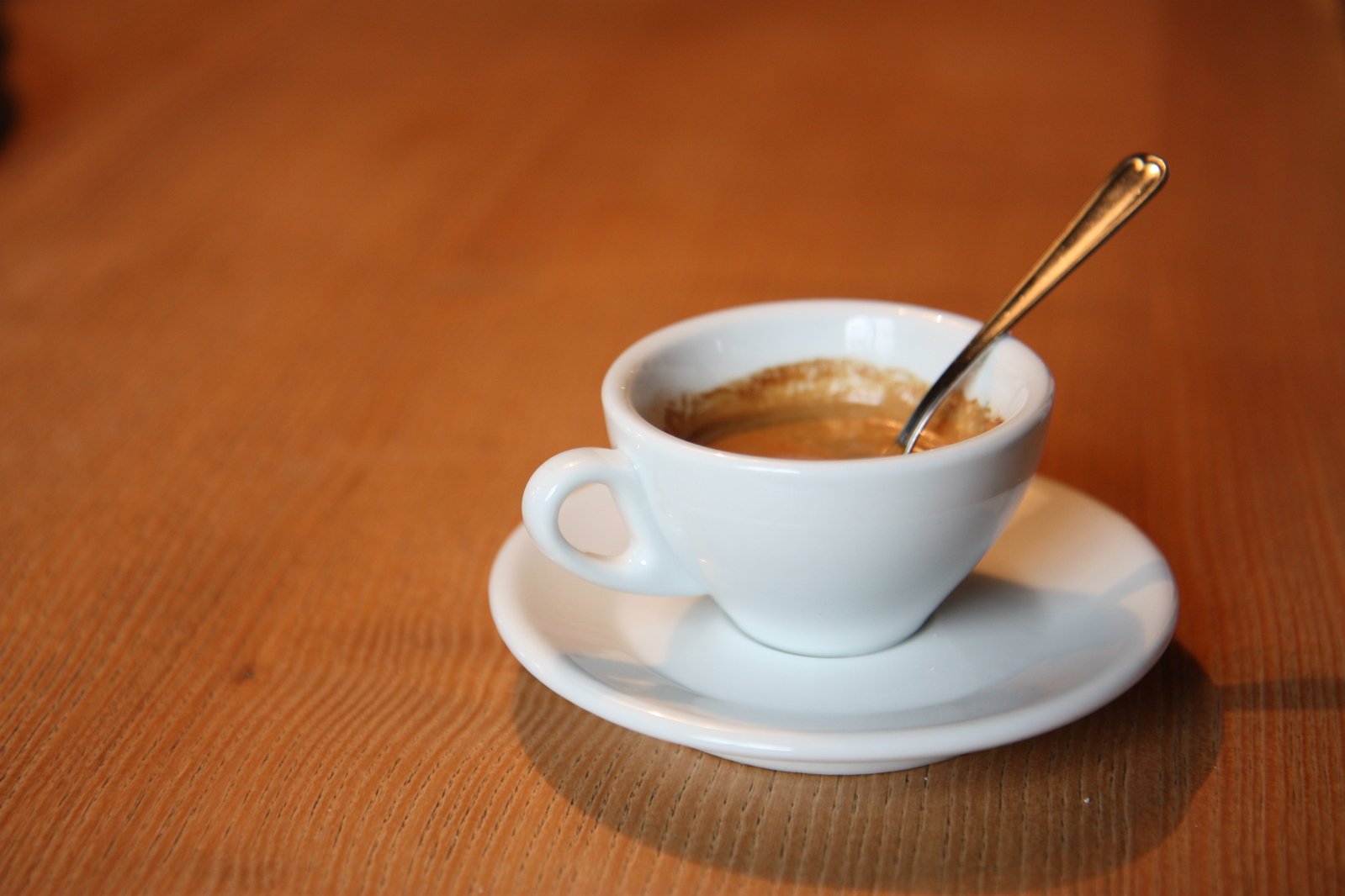 there is a cup of coffee and a spoon on the table