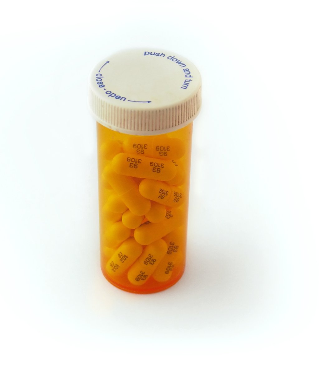 an open jar with orange pills on white surface