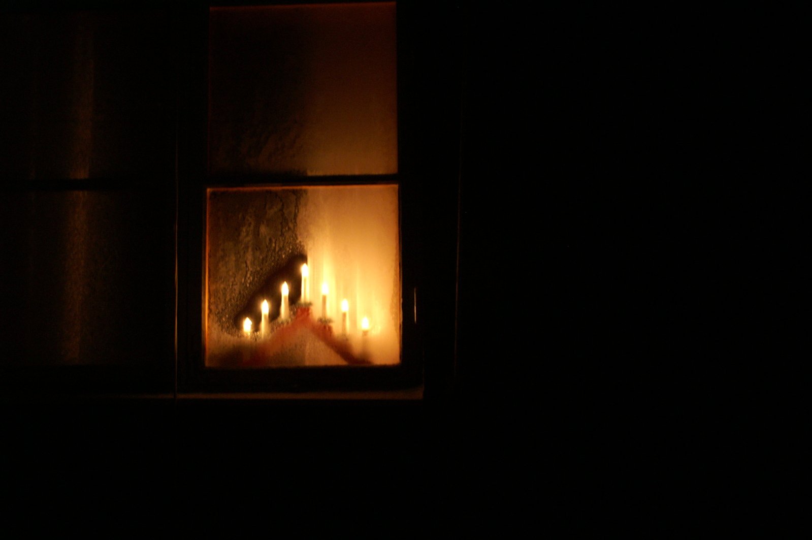 lit candles sitting in an open window at night