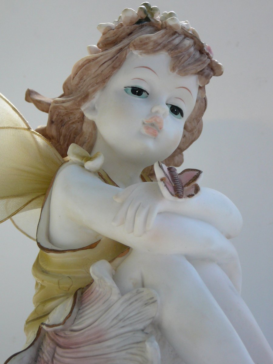an figurine of a beautiful little girl in a dress holding a erfly