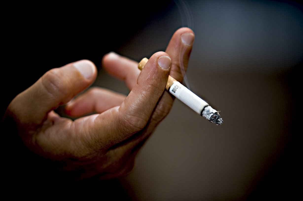 an adult holding a cigarette in their left hand