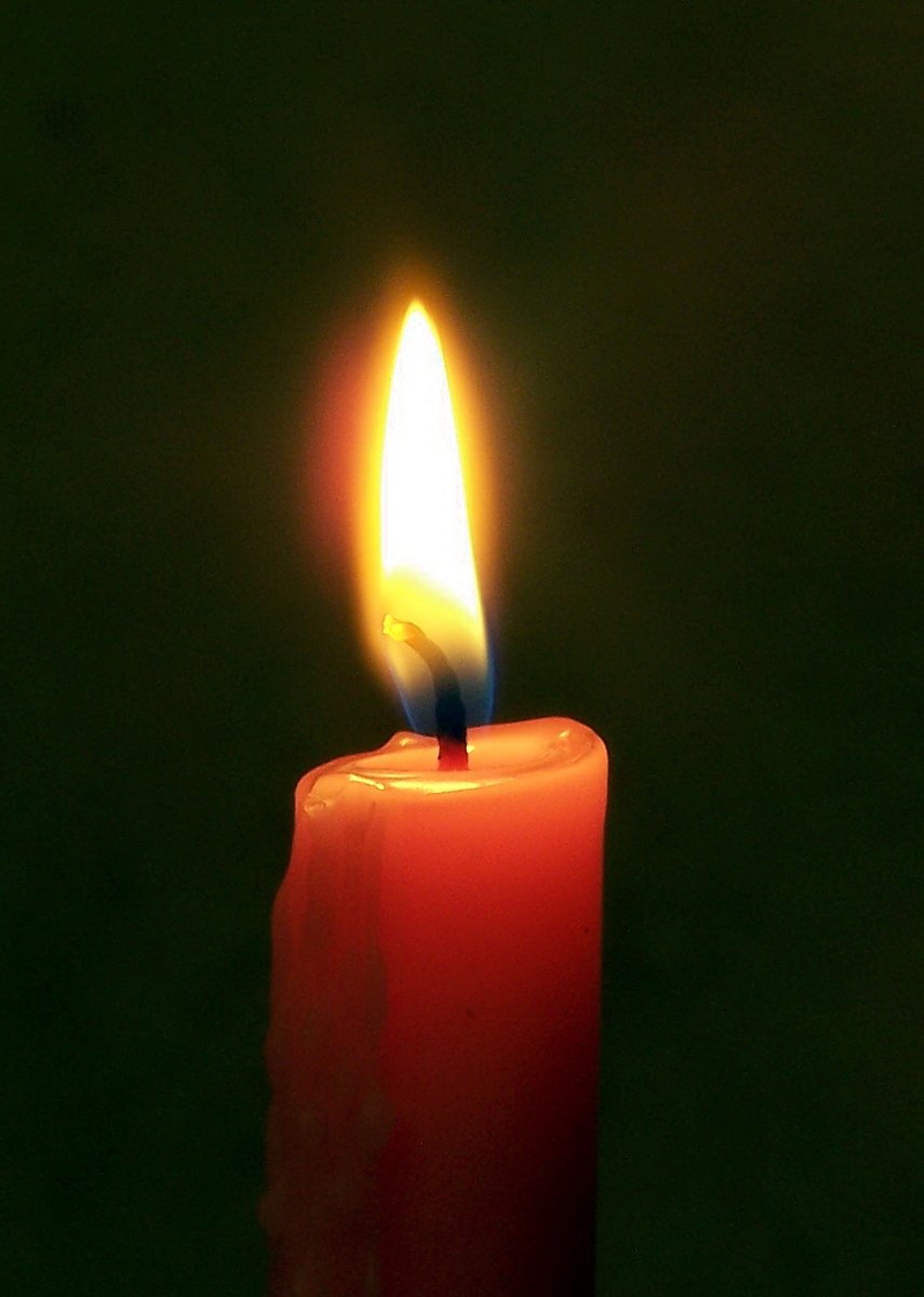red candle glowing on black with bright red flame