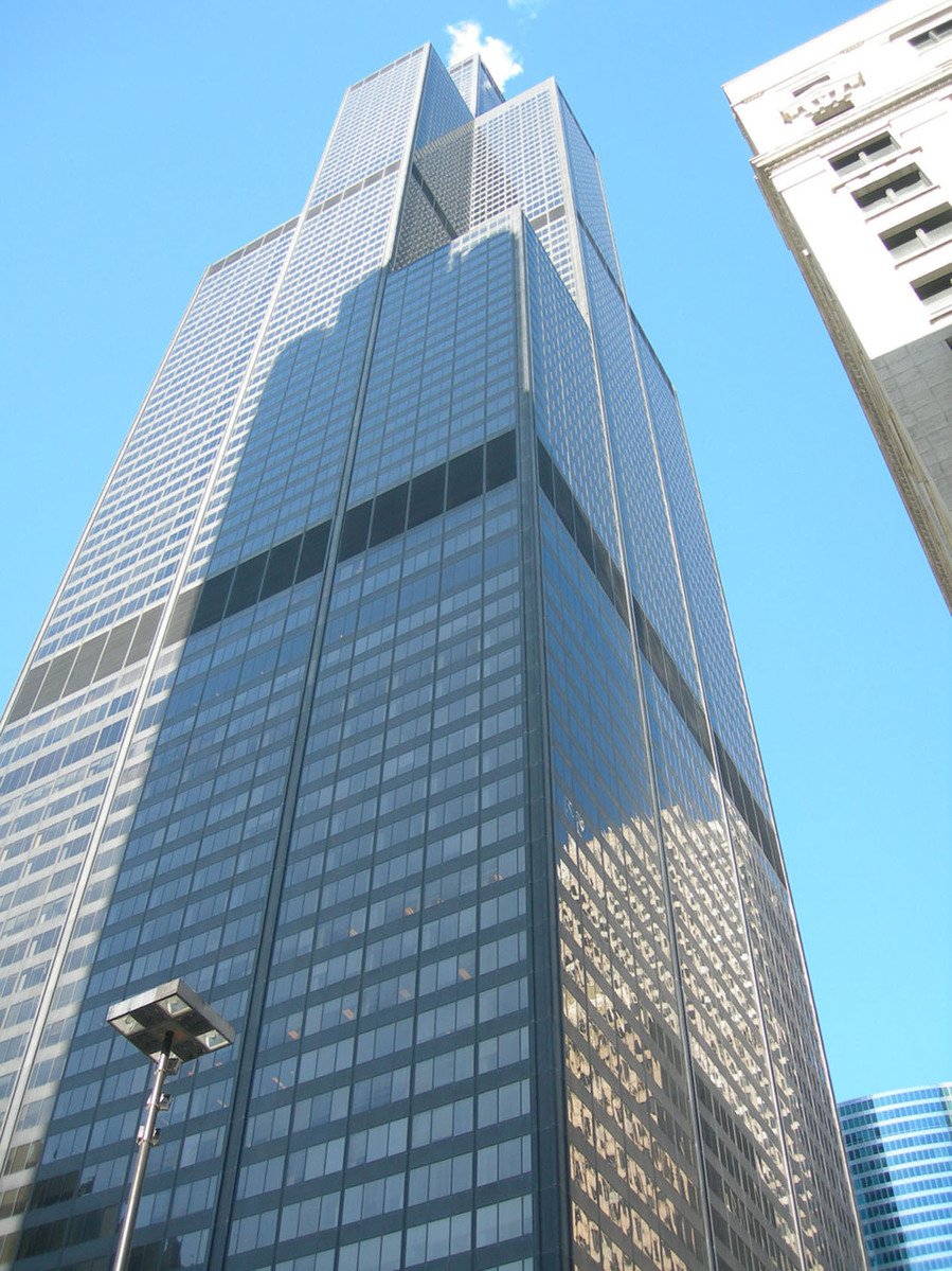 a tall office building with skyscrs and sky in background