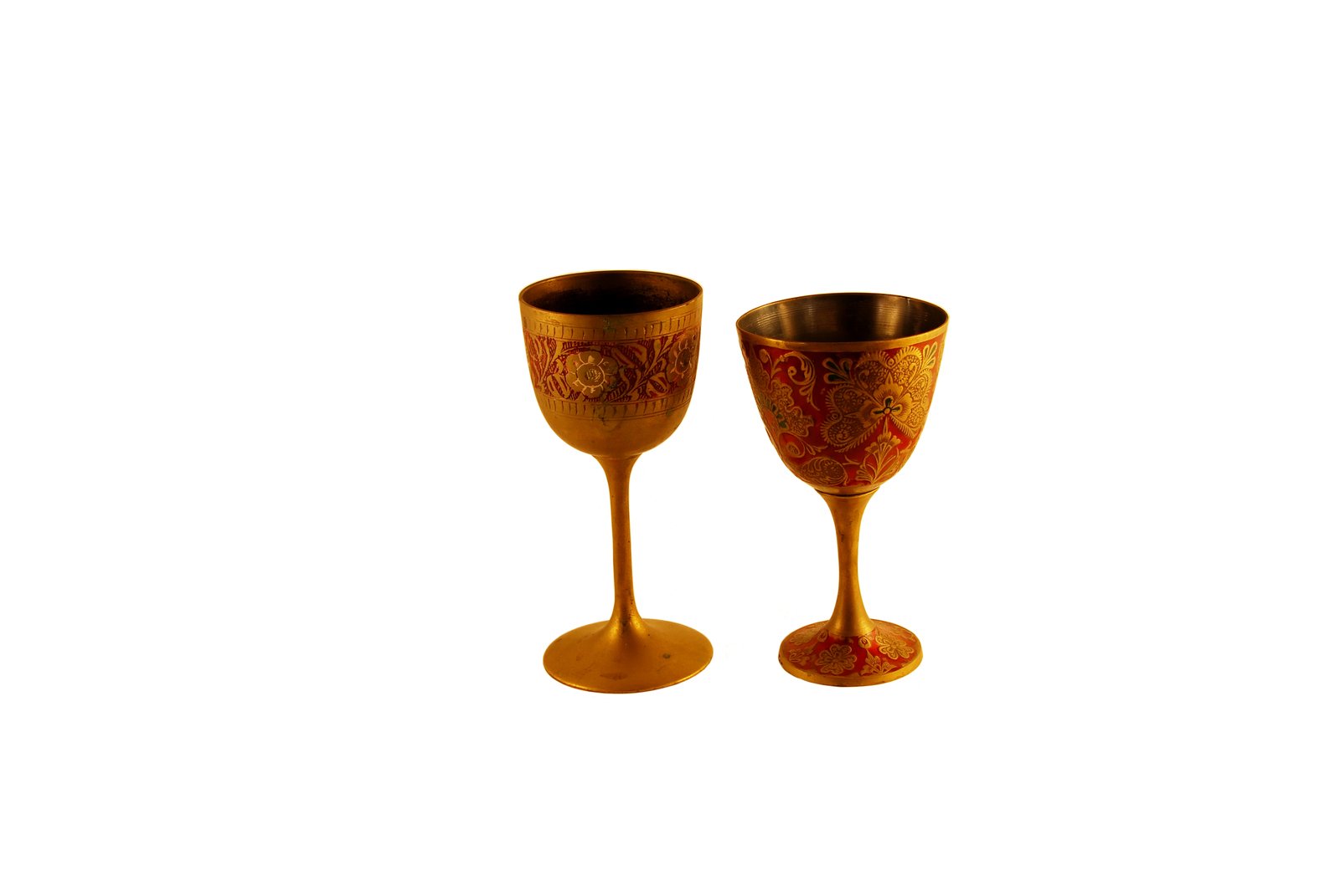 a gold goblet sitting next to a tall gold goblet with a golden design on the outside
