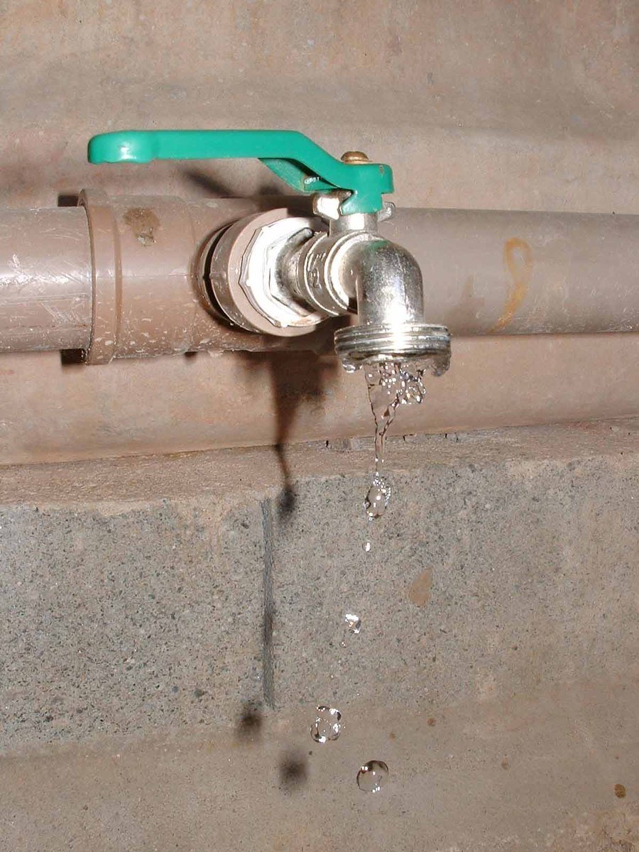 water running out of a metal pipe, with a blue plastic spigot on top