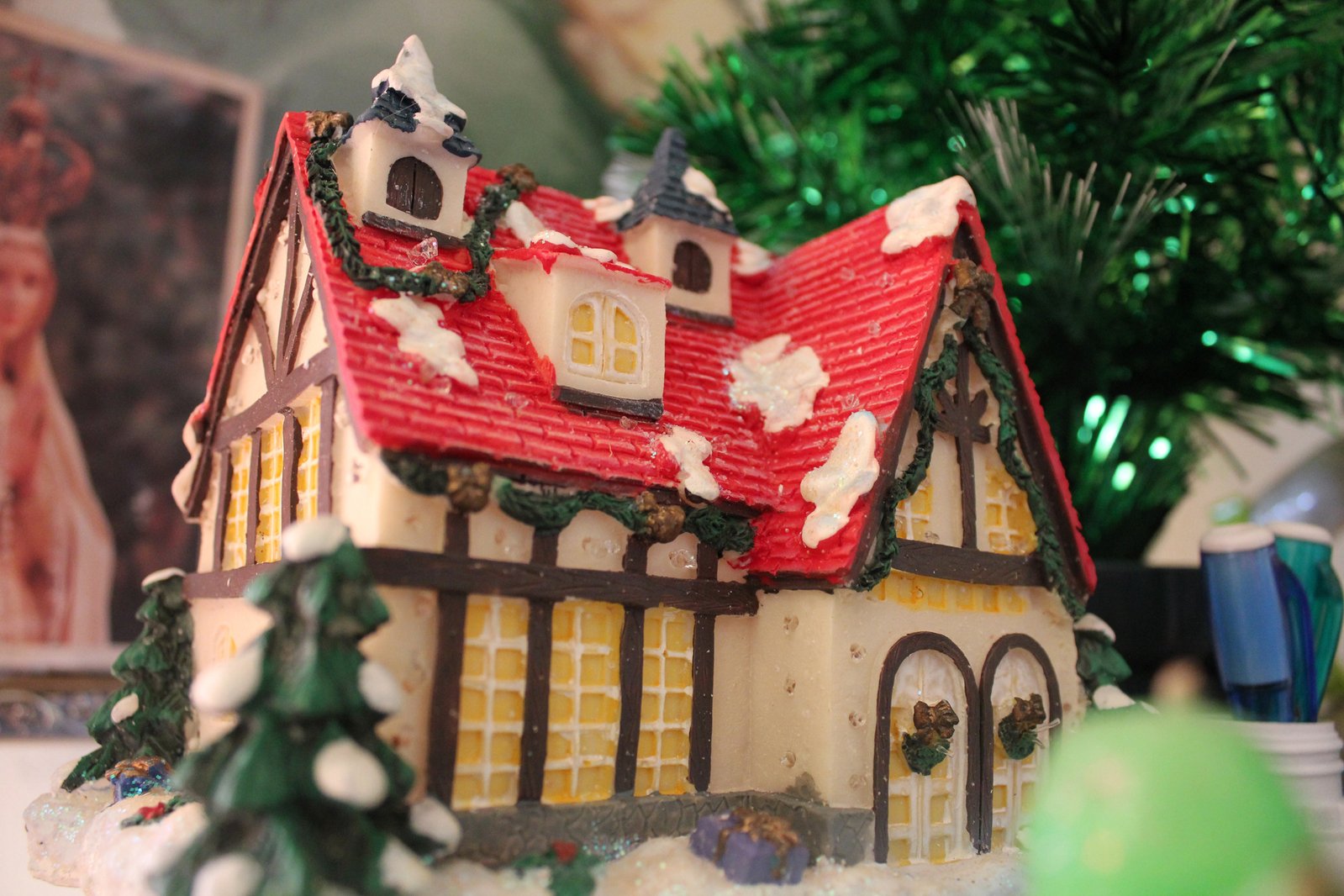 a miniature christmas house with fake trees in front
