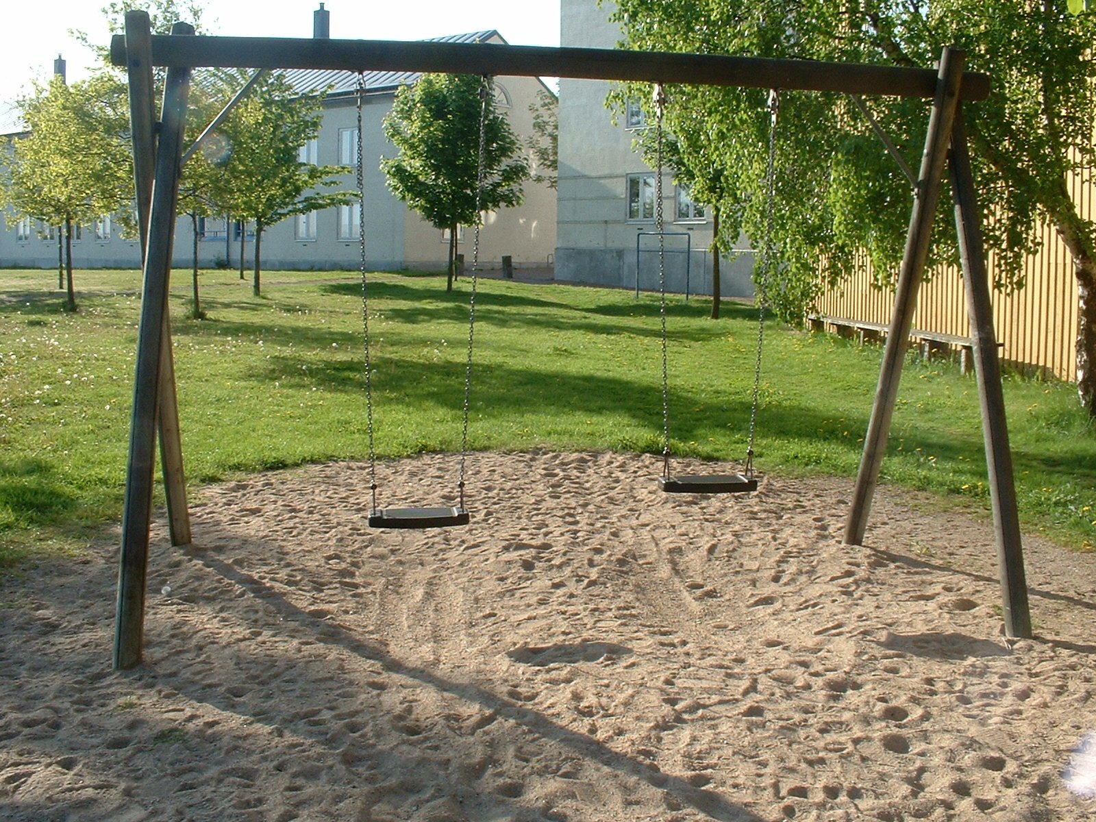 the playground in a back yard with a swing set